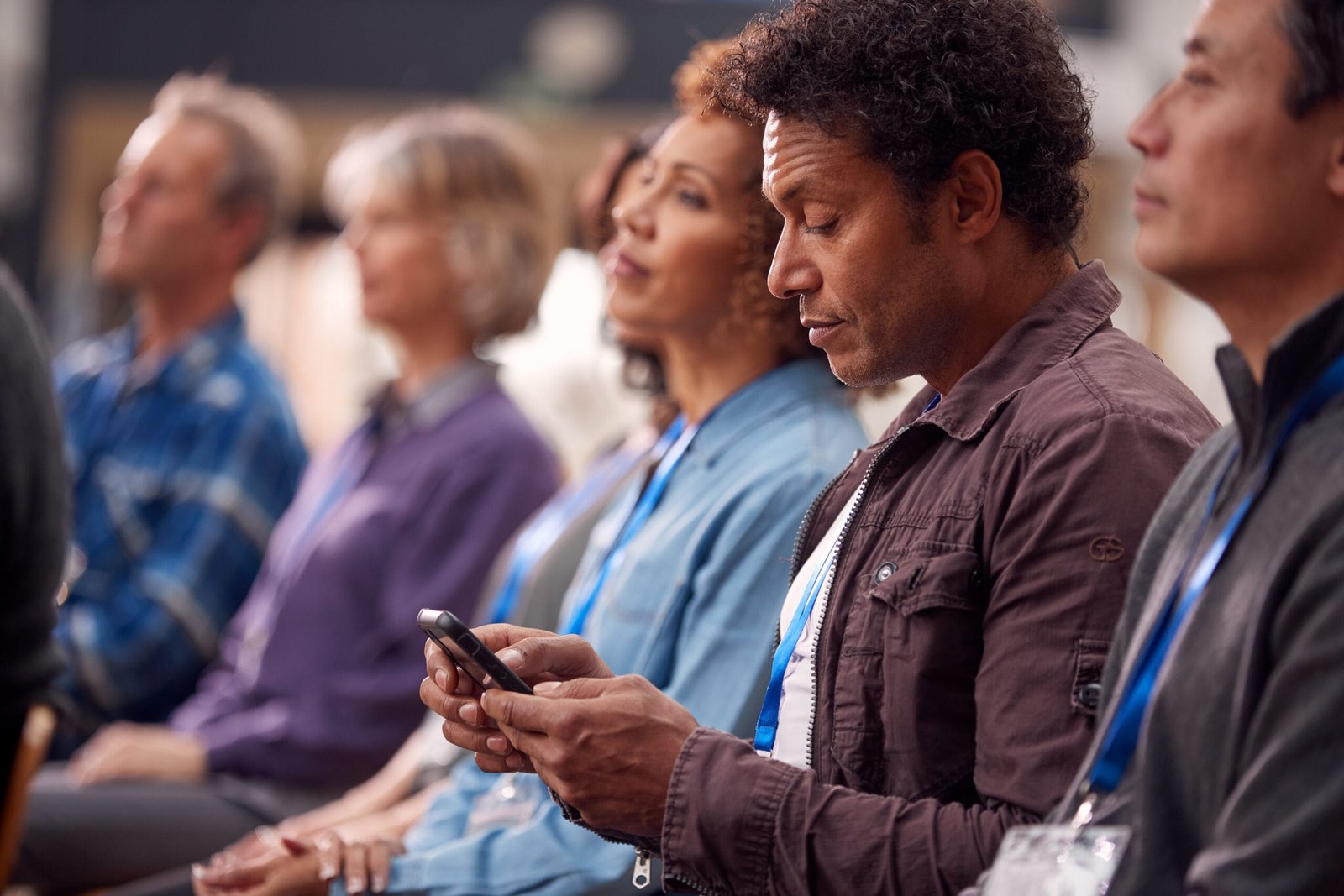Businessman In Presentation At Conference Checking Mobile Phone Event Integrations Benefit Image